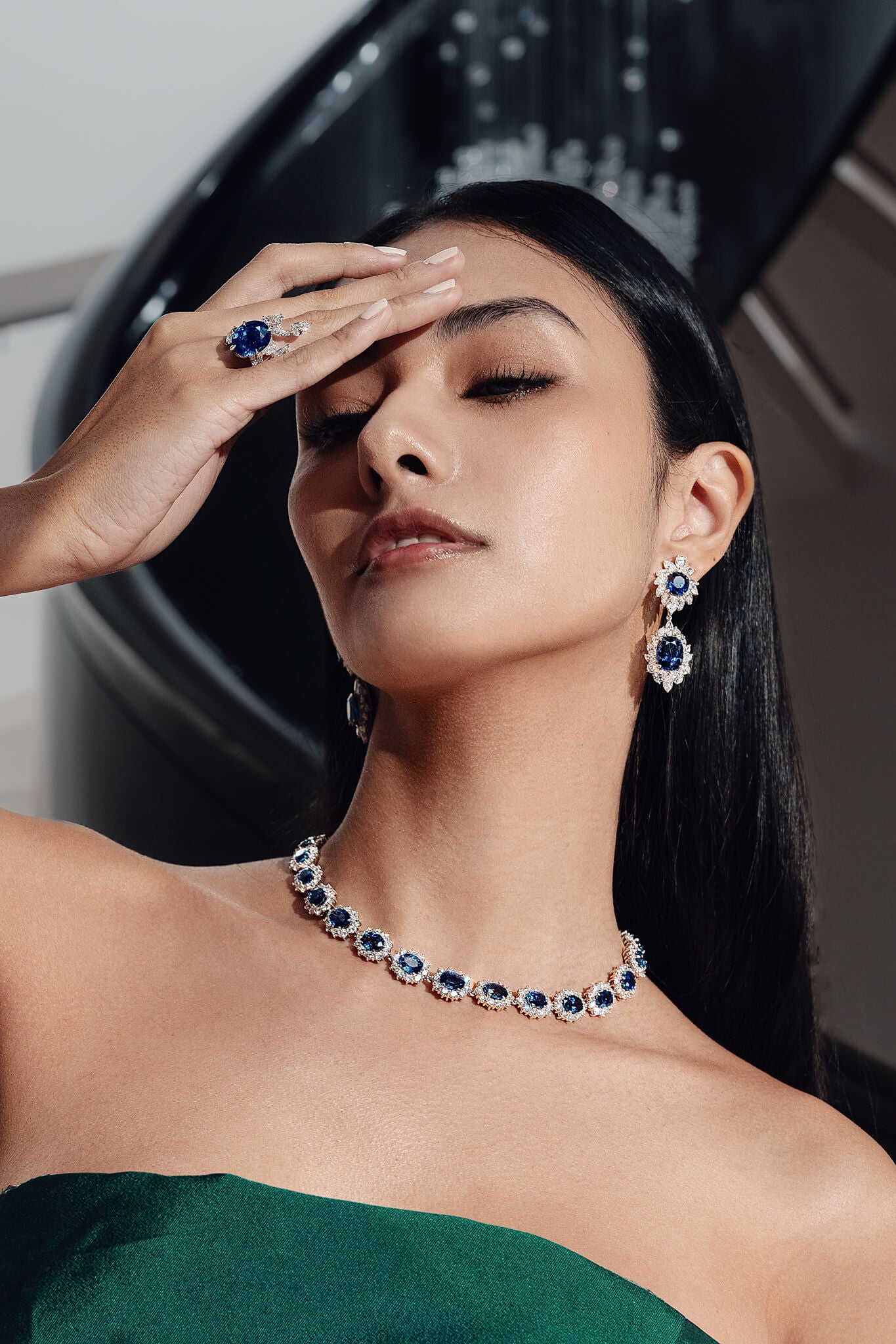Woman wearing a necklace, ring, and earrings with a blurred background