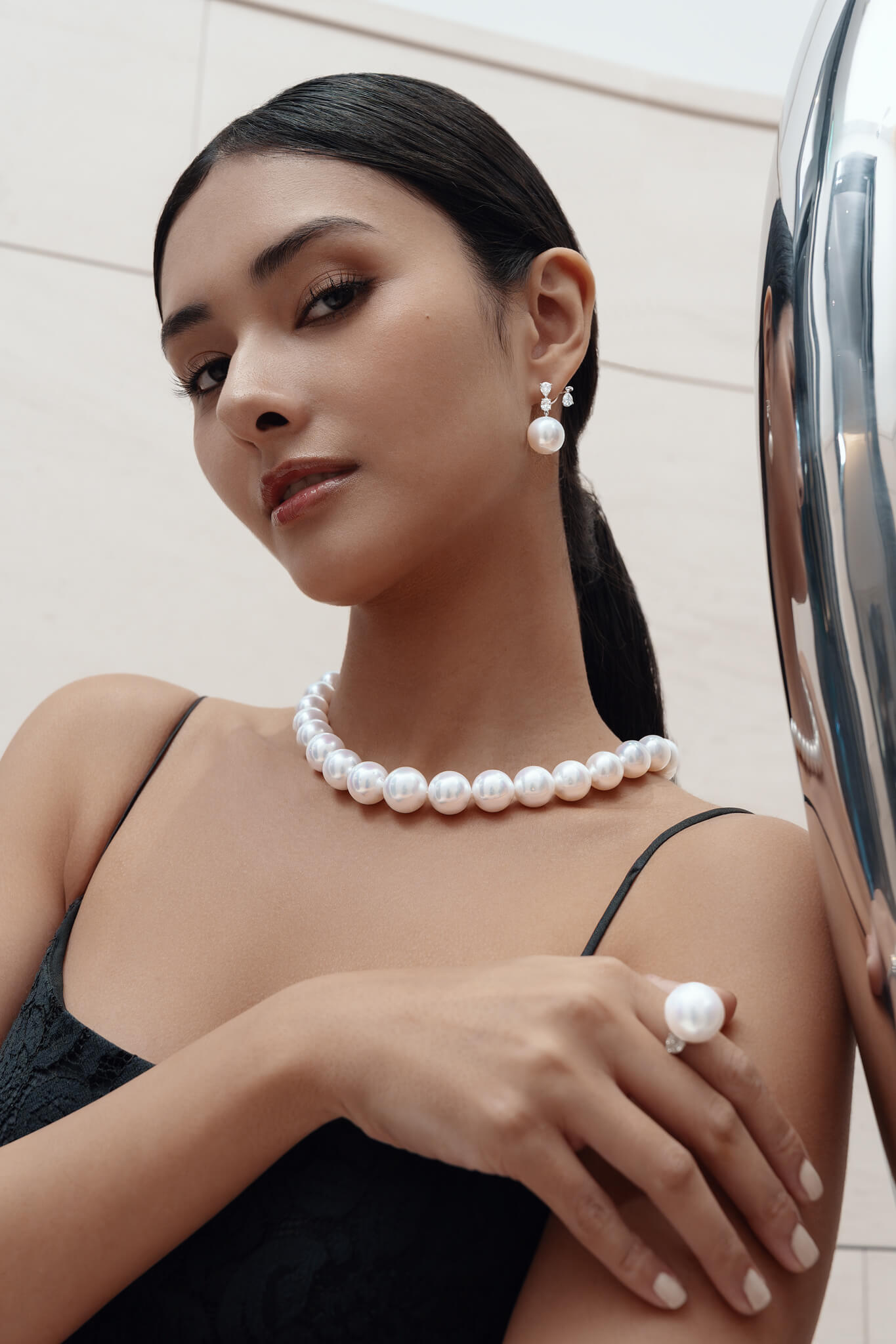 Woman wearing a pearl necklace and earrings with a neutral background